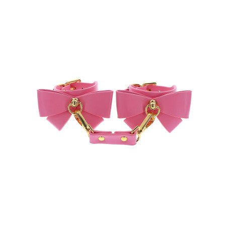 "Manette da polso rosa in stile bondage con dettagli in metallo dorato e cinturini regolabili, presentati con elegante imballaggio, acquistabili online